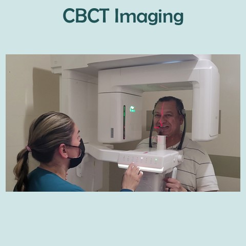 Friendly dental clinic staff obtains cone beam imaging from content patient.