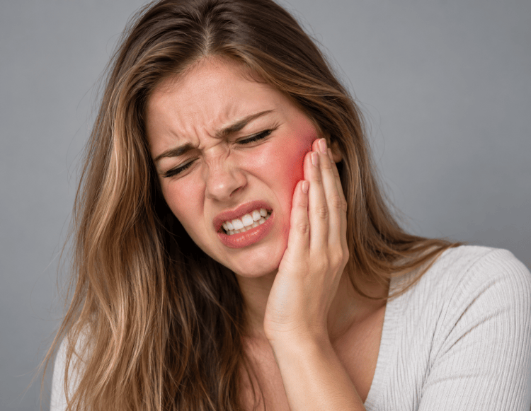 Woman holding her lower left jaw due to tooth pain and toothache.
